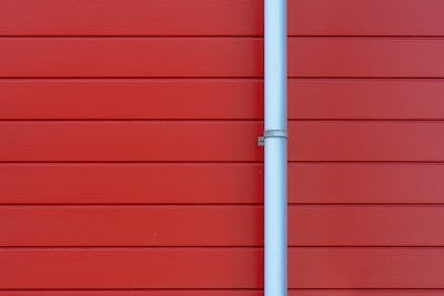 Rain gutter on a building wall showing downspout drainage