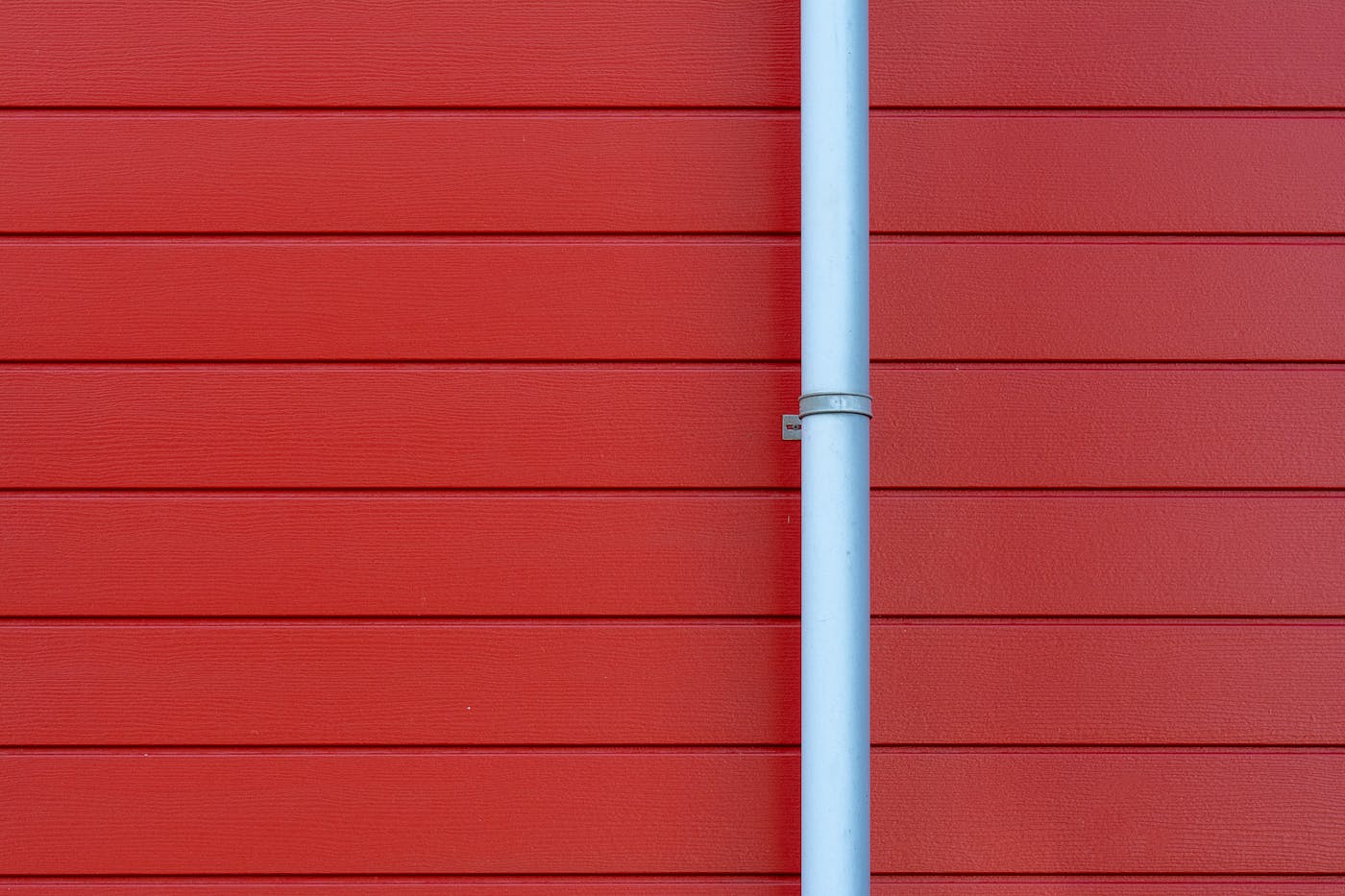 Rain gutter downspout on red wall showing drainage connection point