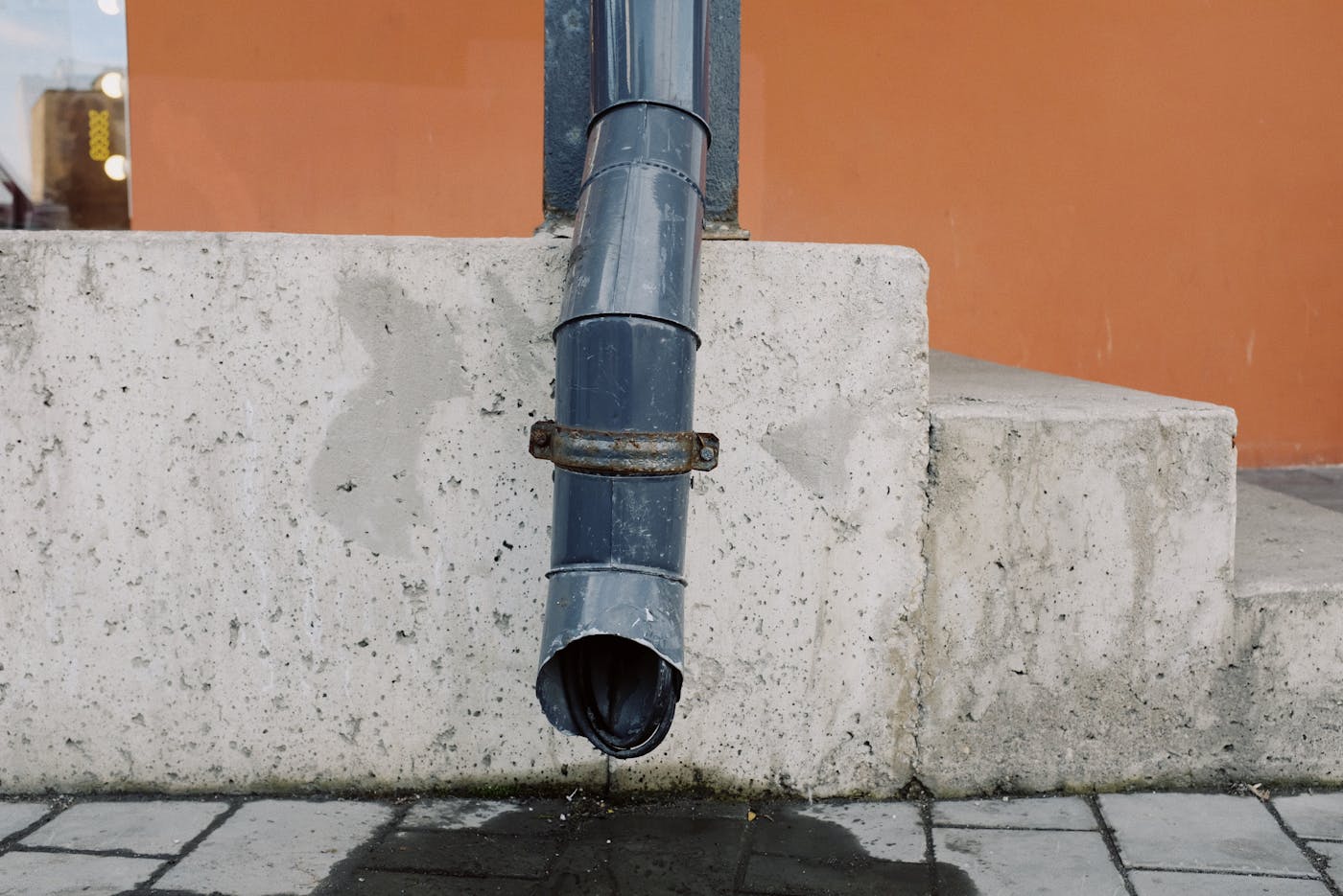 Water dripping from a drain pipe showing what a clogged downspout looks like in Passaic NJ